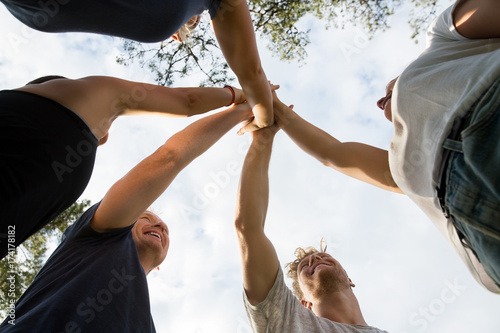 Low Angle View Of Friends Stacking Hands Against Sky
