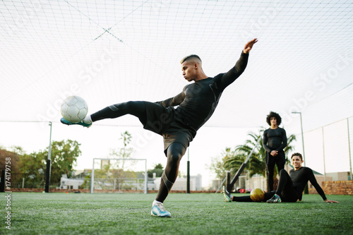 Man kicking soccer ball on field