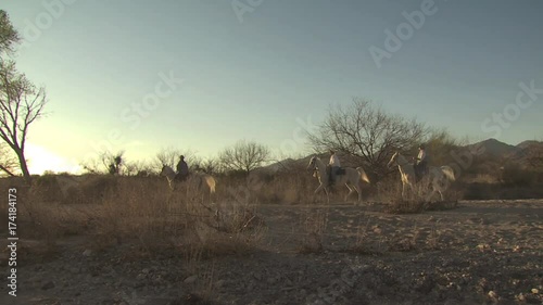 Panoramic View of Three People Riding Horses At Sunset