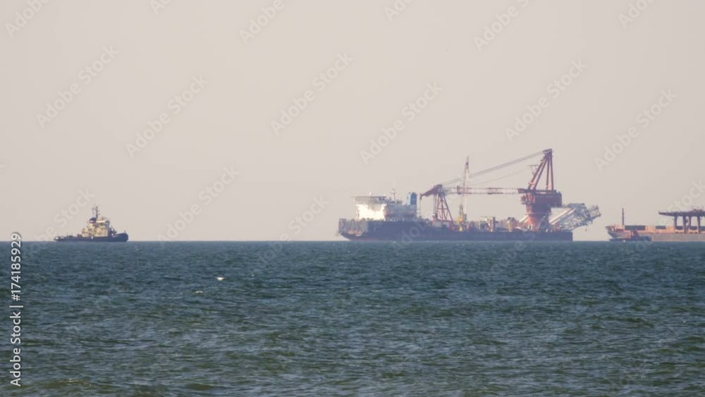 Cargo freighter ship sailing, moving at ocean horizon sky in hazy sea. Multi-purpose vessel carrying bulk cargo on deck across sea. Shipping services Cargo freighter ship sailing, moving at ocean horizon sky in hazy sea. Multi-purpose vessel carrying bulk cargo on deck across sea. Shipping services