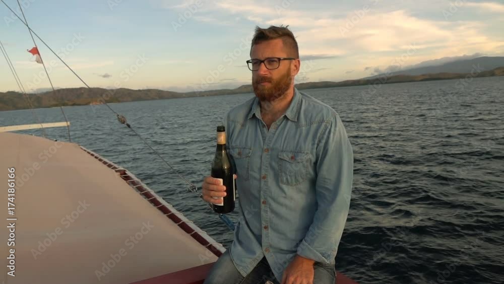 Man sitting on the yacht and holding bottle of champagne, slow motion shot at 240fps, steadycam shot
Man sitting on the yacht and holding bottle of champagne, slow motion shot at 240fps, steadycam shot