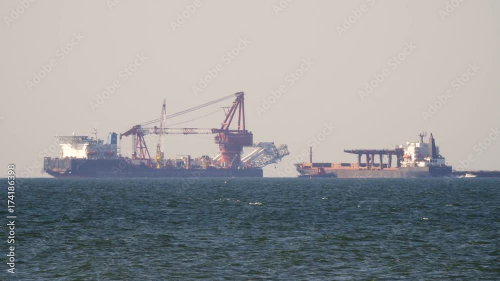 Cargo freighter ship sailing, moving at ocean horizon sky in hazy sea. Multi-purpose vessel carrying bulk cargo on deck across sea. Shipping services Cargo freighter ship sailing, moving at ocean horizon sky in hazy sea. Multi-purpose vessel carrying bulk cargo on deck across sea. Shipping services