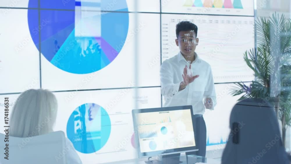  Businessman giving presentation to colleagues in modern glass office