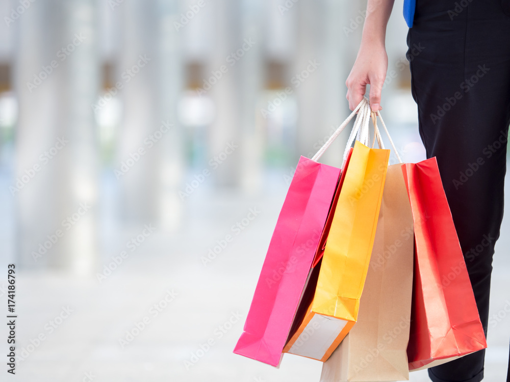 Close up woman holding shopping bag with colorful walking in the city with copyspace