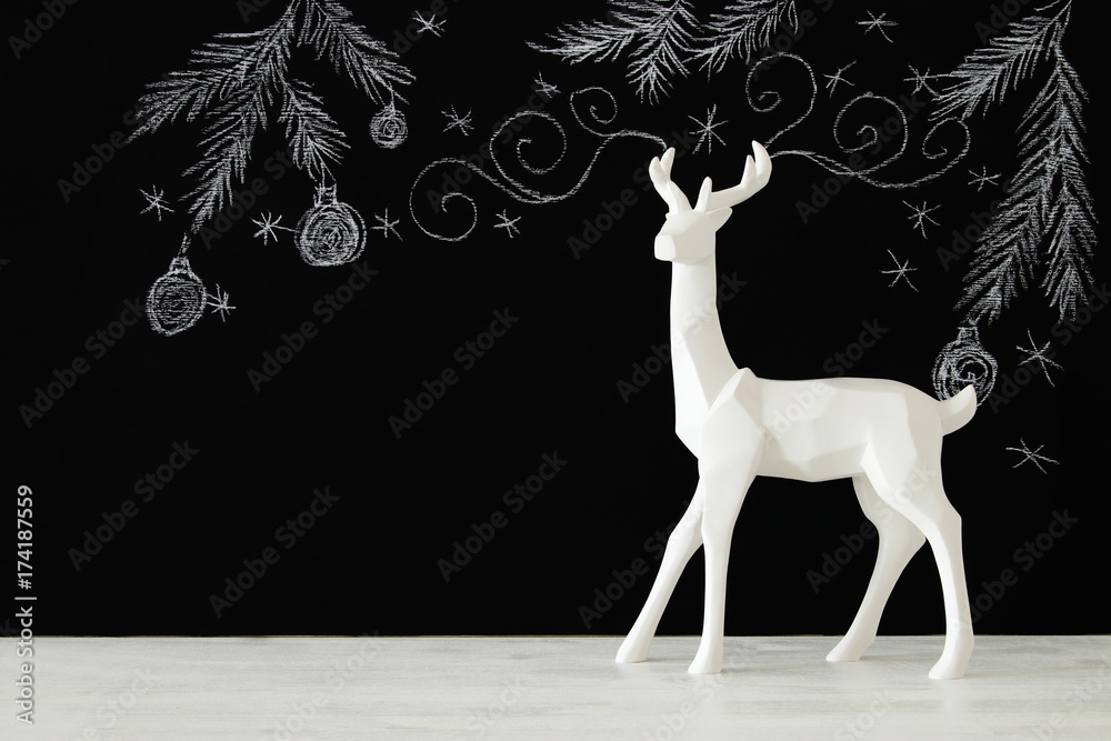 White reindeer on wooden table over chalkboard background whith hand drawn chalk illustrations. White reindeer on wooden table over chalkboard background whith hand drawn chalk illustrations.