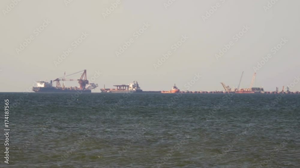 Cargo freighter ship sailing, moving at ocean horizon sky in hazy sea. Multi-purpose vessel carrying bulk cargo on deck across sea. Shipping services Cargo freighter ship sailing, moving at ocean horizon sky in hazy sea. Multi-purpose vessel carrying bulk cargo on deck across sea. Shipping services