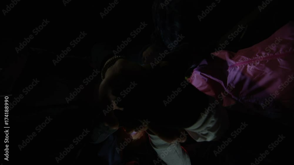 Extreme sports team in the woods at night put hands together for show of unity. Low angle view looking up.