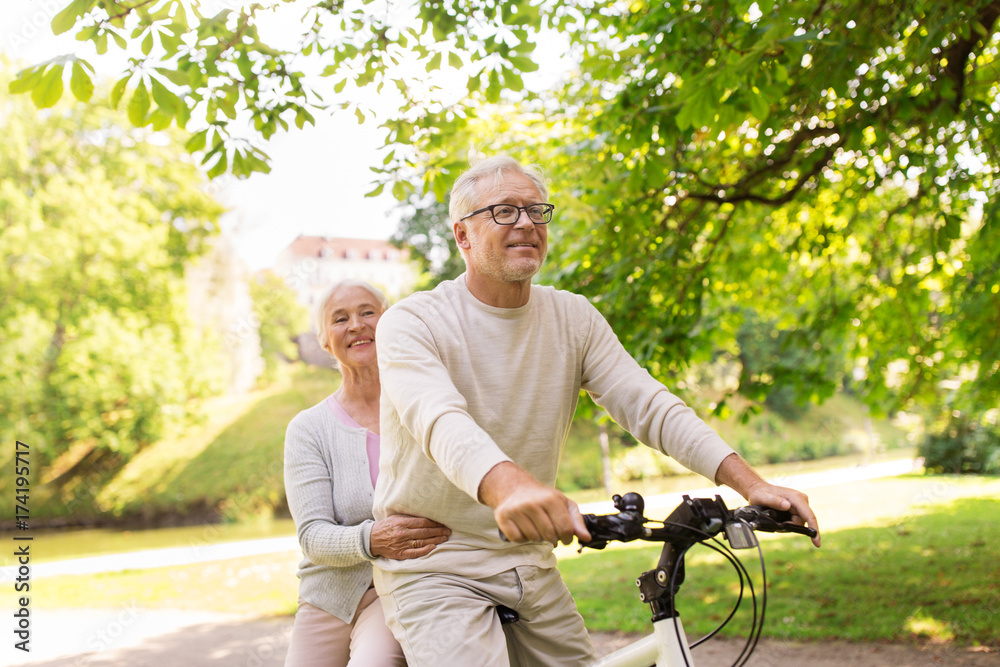happy senior couple riding on bicycle at park