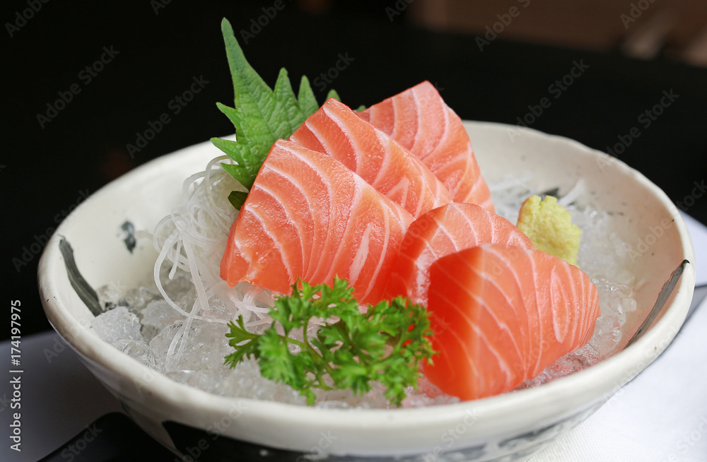 Salmon raw slice or salmon sashimi in Japanese style fresh serve on ice with fresh wasabi on black table. Salmon raw slice or salmon sashimi in Japanese style fresh serve on ice with fresh wasabi on black table.