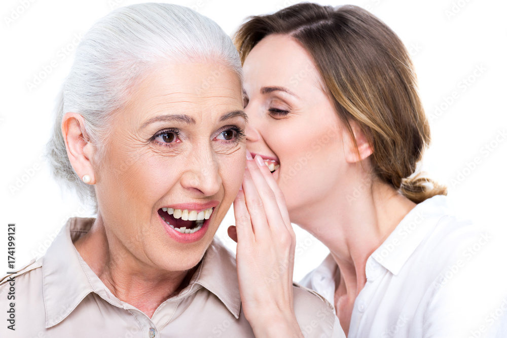 daughter whispering to senior mother daughter whispering to senior mother
