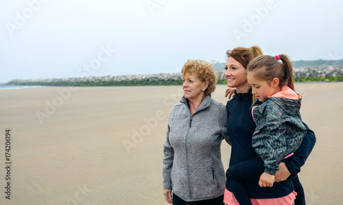 Three generations female looking at sea on the beach in autumn