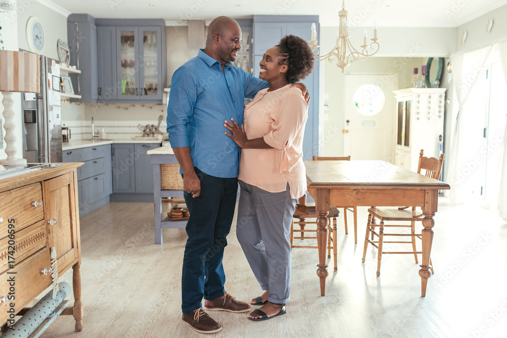 Affectionate African couple smiliing and standing together in their kitchen Affectionate African couple smiliing and standing together in their kitchen
