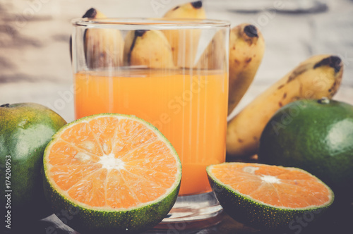 Fototapeta Naklejka Na Ścianę i Meble -  a glass of freshly squeezed orange juice and fresh tropical fruits