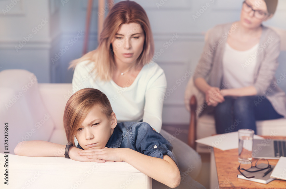 Depressed boy and his mother sitting in the office of psychologist Depressed boy and his mother sitting in the office of psychologist