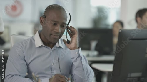  Friendly customer service operator talking to customer in busy call centre