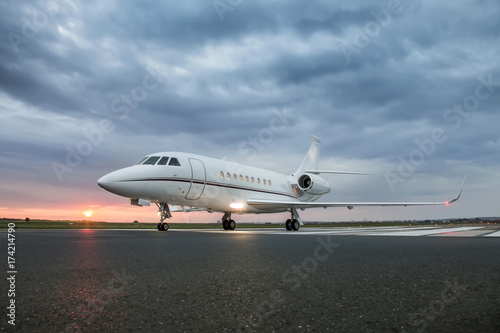 Obraz na plátně Modern advanced private business jet ready to take off with sunrise in the backg