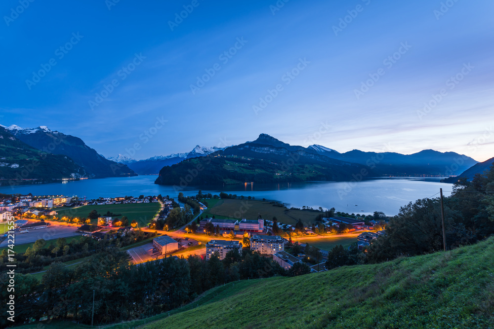 Night. Canton Schwyz, Brunnen town. Night panorama of Lake Lucerne. Mountain range, snow on the tops of the mountains. Lights in the houses and along the road.  Switzerland, 