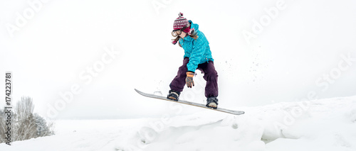 Young woman on the snowboard jumping