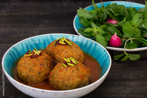 Koofteh Tabrizi Large Meatballs Stuffed With Dried Fruits And Nuts In Tomato Turmeric Broth A Traditional Azeri And Iranian Dish Served In Turquoise Bowl Garnished With Pistachio and Barberries