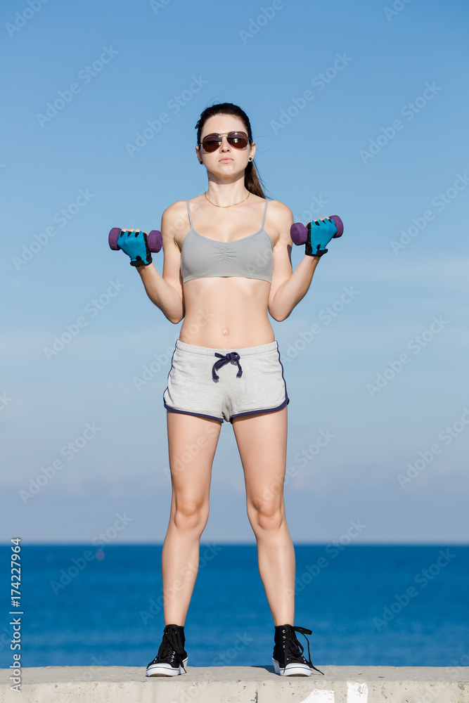 Girl with dumbbells exercising on embankment Girl with dumbbells exercising on embankment