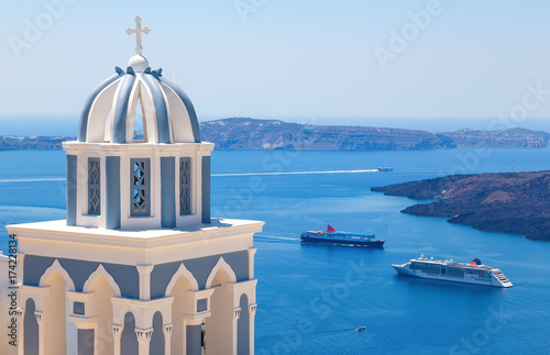 Sun shining through belltower of church with a view of Santorini volcanic caldera and ships in it, Santorini, Cyclades, Greece