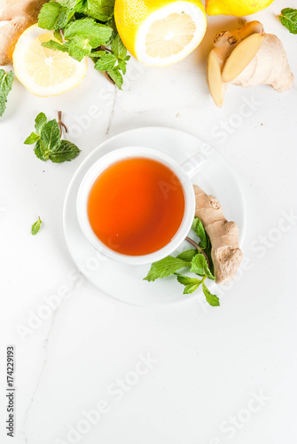 Cup of ginger tea with lemon,fresh mint and honey, on white marble table, copy space top view