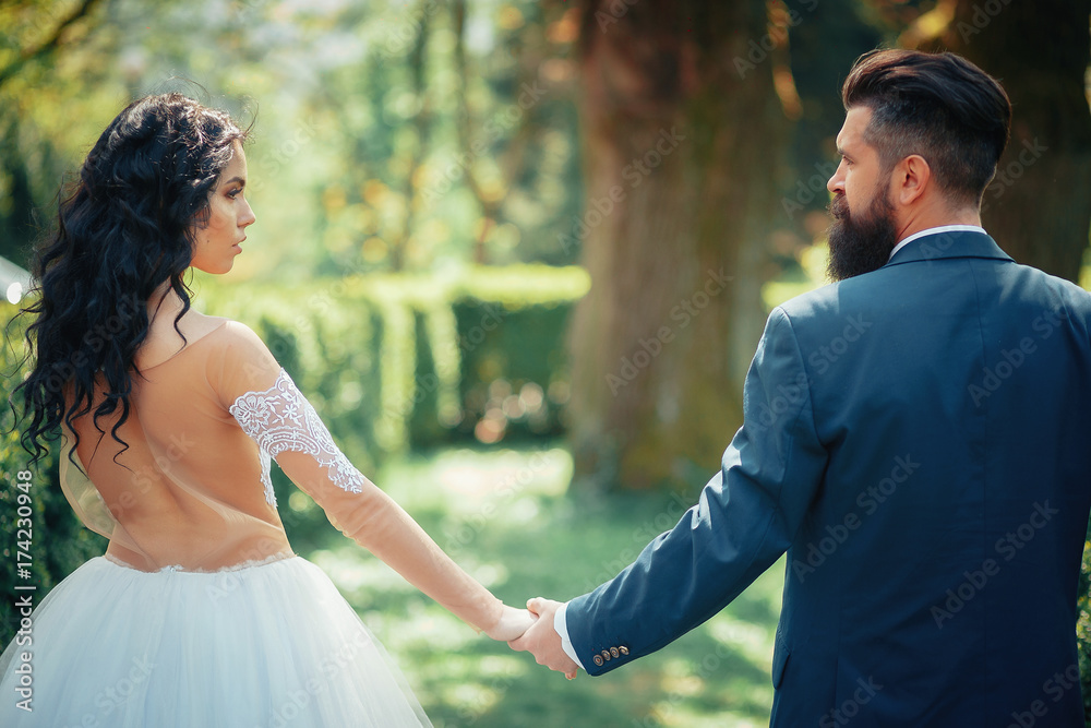 A beautiful brunette in a wedding dress and a bearded bride walking in the park A beautiful brunette in a wedding dress and a bearded bride walking in the park