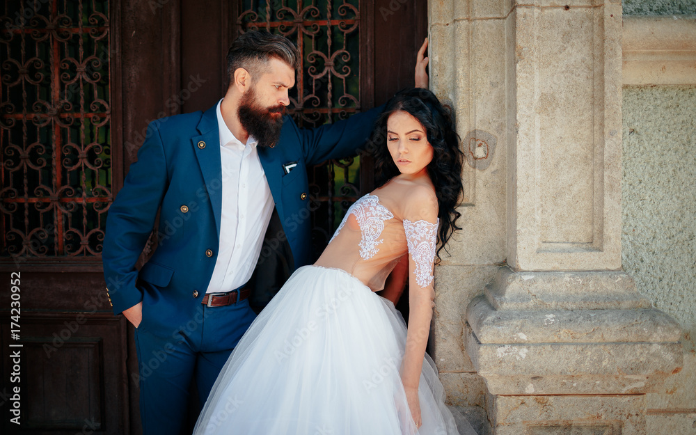 A beautiful brunette in a wedding dress and a bearded bride walking around an ancient castle