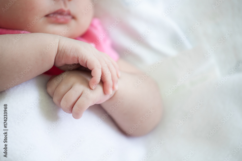 Newborn baby girl hands holding while she sleeping on white blanket Newborn baby girl hands holding while she sleeping on white blanket