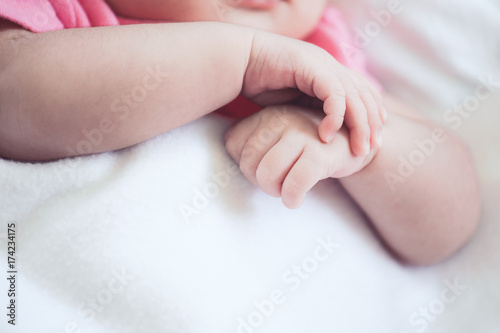 Newborn baby girl hands holding while she sleeping on white blanket