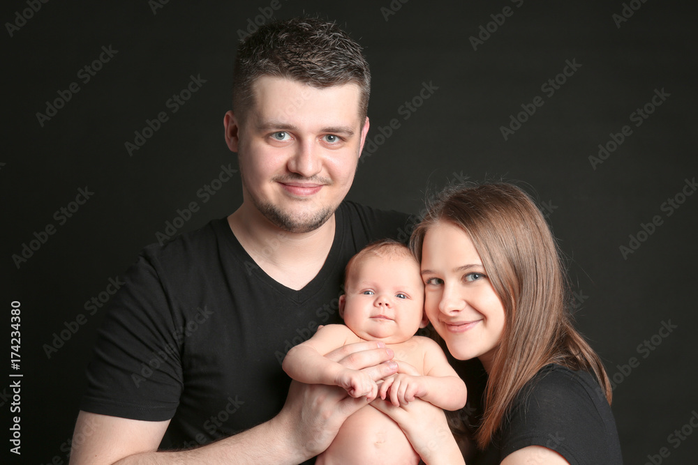 Happy young family holding newborn on black background Happy young family holding newborn on black background