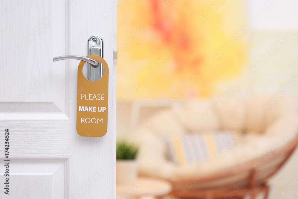 Fototapeta premium Open door with sign PLEASE MAKE UP ROOM on handle at hotel