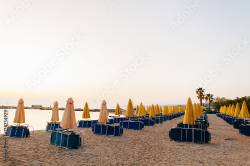 Yellow umbrellas and beach chairs at the at Aegean Sea beach. Start of season concept