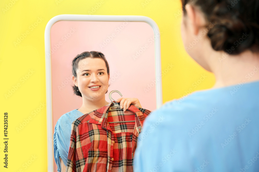Beautiful overweight woman standing near mirror at store Beautiful overweight woman standing near mirror at store