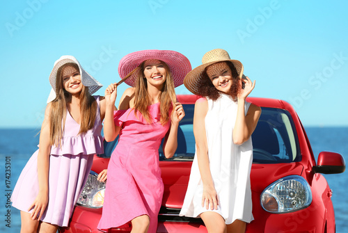 Beautiful young women near car at sea resort