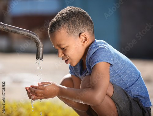 Canvas Print African American child drinking water from tap outdoors