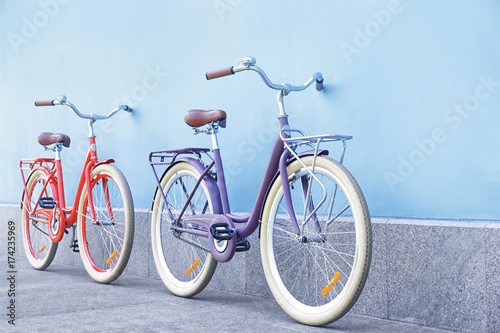 Stylish new bicycles near color wall outdoors