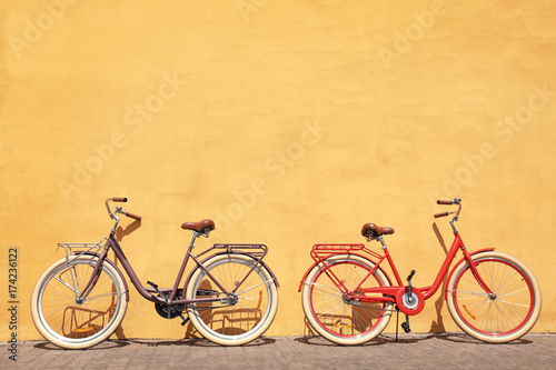 Two stylish new bicycles near color wall outdoors