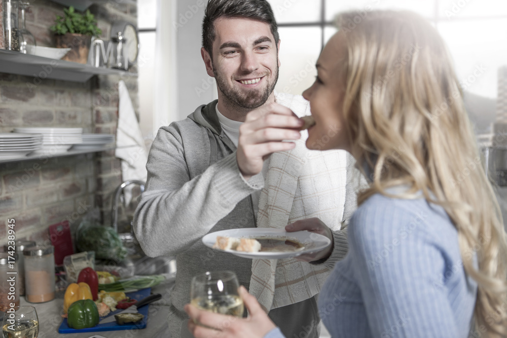 Couple tasting food together in kitchen Couple tasting food together in kitchen