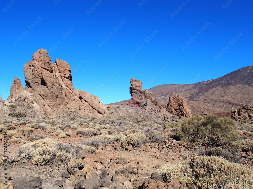 mountain and volcanic rock formations in teide national park in tenerife with clear blue sky