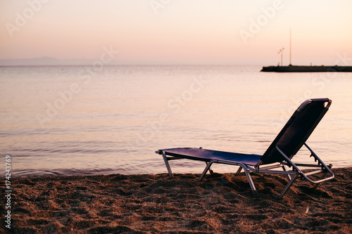 Empty free lonely sun lounger at Aegean Sea beach on the sunset, Greece. End of season concept.