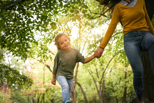 Mother an daughter in meadow. Mother and daughter holding hands and running together trough park. © liderina