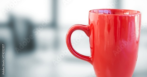 Red coffee cup against blurry grey office