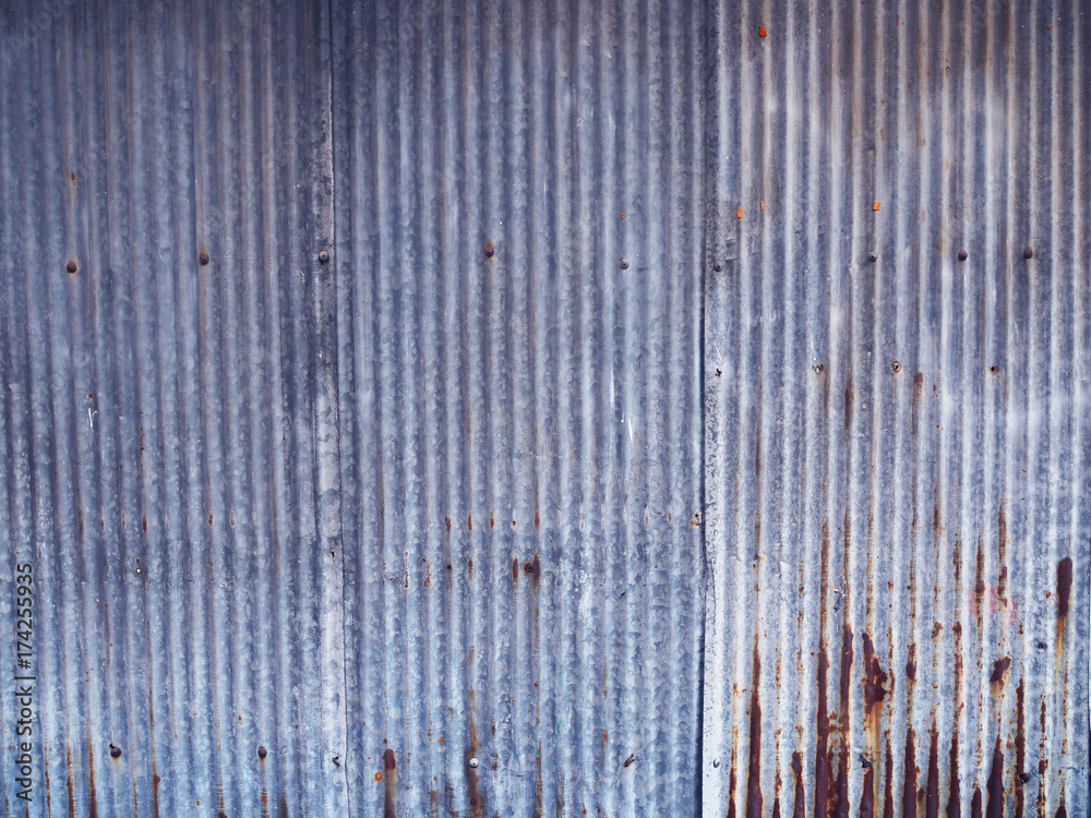 Rusty blue grey dirty stained weathered wavy zinc metal board iron fence wall background Rusty blue grey dirty stained weathered wavy zinc metal board iron fence wall background