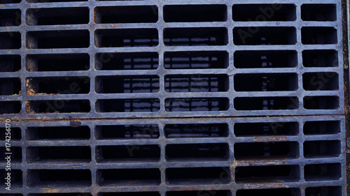 Top view rusty black grey steel rectangle hole tile pattern mesh sewage drainage cover with water shadow reflection background