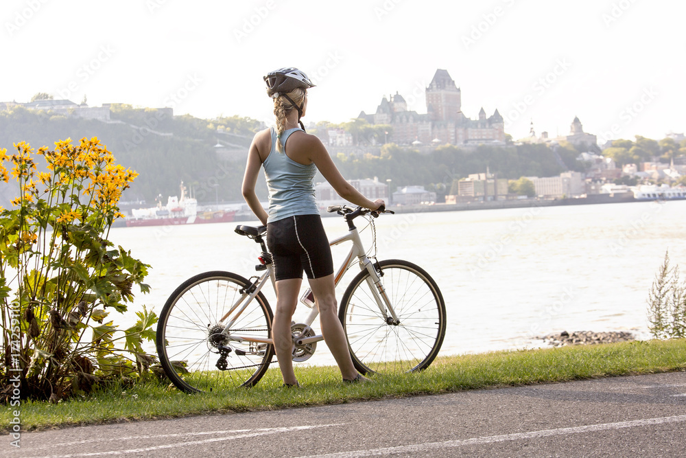 Obraz premium Young Woman Riding Bike outside with quebec view