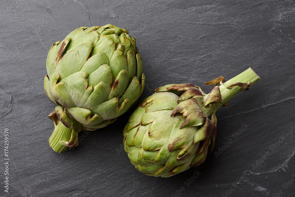 Fresh ripe artichokes close up on textured stone background, top view Fresh ripe artichokes close up on textured stone background, top view