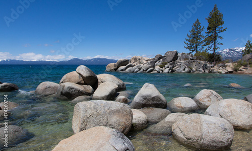 Sand Harbor, Lake Tahoe, Nevada, with blue sky, rocks in foreground and mountains in the distance