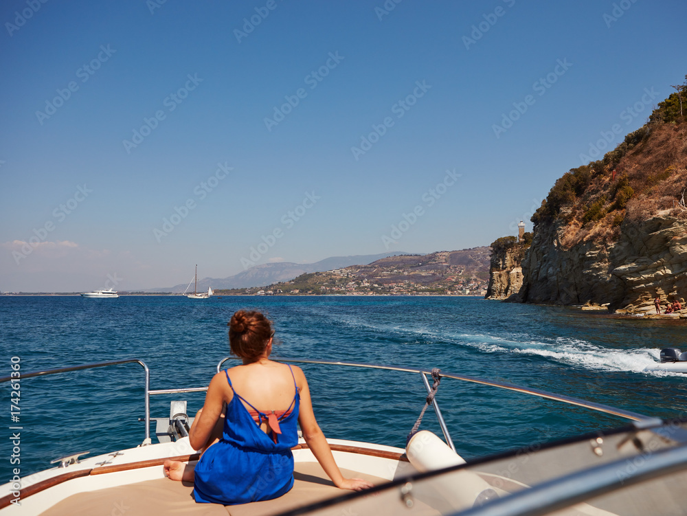 Woman on boat deck coastline in background