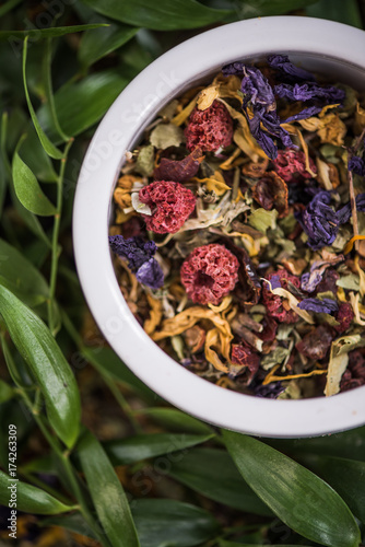 Aromatic colorful tea in pot over green leaves photo